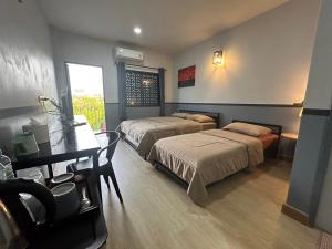 a bedroom with two beds and a desk and a table at บ้านสุขซอย5 in Kanchanaburi City