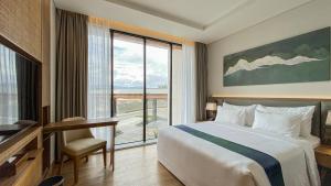 um quarto de hotel com uma cama e uma grande janela em Marianna Resort & Convention Tuktuk Samosir em Ronggurnihuta