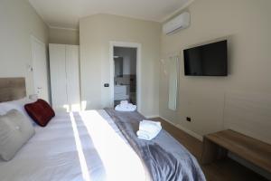 1 dormitorio con 1 cama blanca grande y TV de pantalla plana en B&B Residenza Alba Chiara, en Monticelli dʼOngina