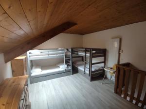 a room with three bunk beds and a wooden ceiling at Appartement T3 50m² - 6 pers. - Barcelonnette in Barcelonnette