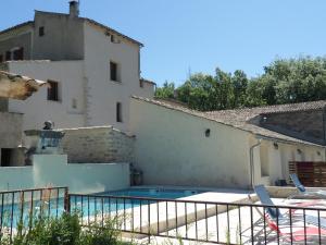 a villa with a swimming pool in front of a building at Les Ânes de Forcalquier in Forcalquier