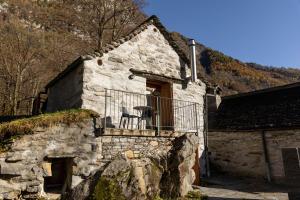 a stone house with a balcony with a chair on it at Verzasca Lodge Elma in Sonogno