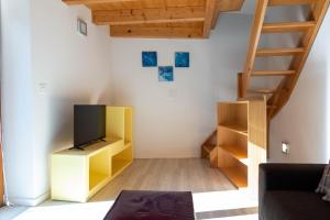 a living room with a tv and a staircase at Verzasca Lodge Elma in Sonogno