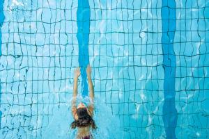 a woman is underwater in a swimming pool at Hotel Adula in Flims