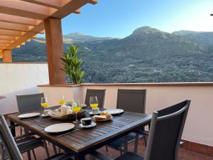 a wooden table with chairs and wine glasses on a balcony at La Casa del Ciervo Sierra Nevada in Güéjar-Sierra