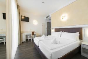 a hotel room with two beds and a desk at Hotel Sogno del Benaco in Limone sul Garda