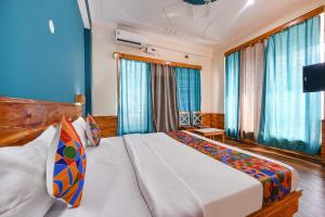 a bedroom with a large bed with blue curtains at FabHotel Snower in Lārji
