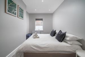 a bedroom with a white bed with two teddy bears on it at Luxury Flat with private terrace in the Heart of Kingston in London