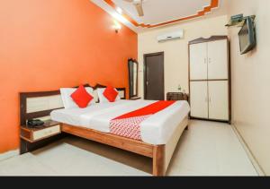 a bedroom with a bed with an orange wall at Hotel sunrise in Lucknow +21 photos