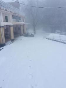 a snow covered street in front of a building at BRIGHTLANDS HOTEL in Murree