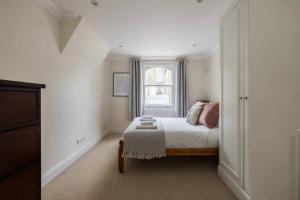 een witte slaapkamer met een bed en een raam bij The West Kensington Collection in Londen