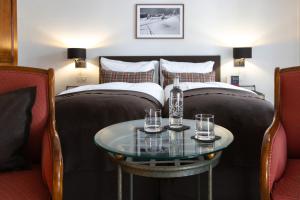 a hotel room with two beds and a table with glasses at Hotel Adula in Flims