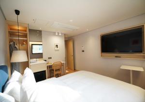 a hotel room with a large white bed and a desk at Nampo Ocean2Heaven Hotel& Spa in Busan