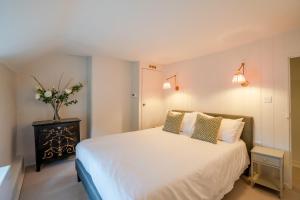 a bedroom with a white bed and a vase of flowers at Sloe Manor Cottage in Chipping Norton