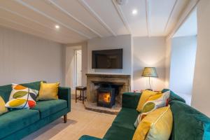 a living room with a green couch and a fireplace at Sloe Manor Cottage in Chipping Norton