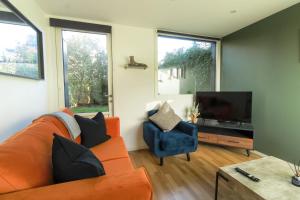 ein Wohnzimmer mit einem orangenen Sofa und einem TV in der Unterkunft 4 Bed MK Cosy & Well equipped House in Shenley Church End
