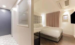 a white bedroom with a bed and a window at Sillim Dominique Hotel in Seoul