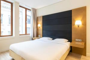 a bedroom with a large bed and two windows at B-aparthotel Grand Place in Brussels