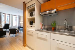 a kitchen with white cabinets and a living room at B-aparthotel Grand Place in Brussels