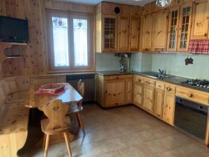 a kitchen with wooden cabinets and a table and a sink at CASA PIAZZALE ALPINI in Schilpario