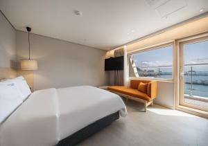 Nampo Ocean2Heaven Hotel& Spa في بوسان: غرفة نوم بسرير ابيض كبير ونافذة