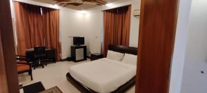 a bedroom with a bed and a desk and a television at Capri Executive in Islamabad