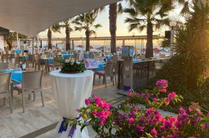 庫薩達斯的住宿－Batıhan Beach Resort & Spa，餐厅设有桌椅,棕榈树和鲜花盛开