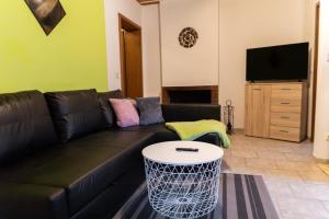 a living room with a black leather couch and a table at NEU! Reiterhof Finkenmühle Fewo Dolly in Weißenstadt