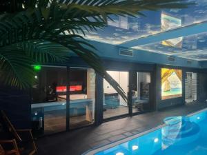 a house with a palm tree in front of a swimming pool at Bella apartman in Mladenovac