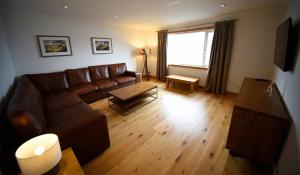 uma sala de estar com um sofá de couro castanho e uma mesa em Shoreside em The Braes