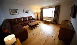 a living room with a brown leather couch and a table at Shoreside in The Braes