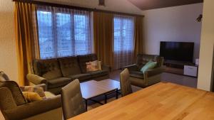 a living room with couches and a table and a television at Tgèsa Val in Sedrun