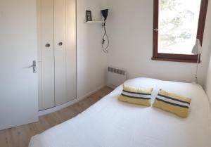 a bedroom with a white bed with two pillows on it at Appartement T3 50m² - 6 pers. - Barcelonnette in Barcelonnette