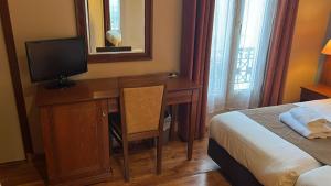 a bedroom with a desk with a bed and a television at 121 Paris Hotel in Paris