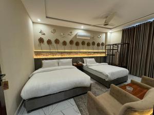 a hotel room with two beds and a couch at Shelton Boulevard Hotel Lahore in Lahore