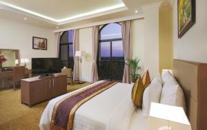 - une chambre avec un grand lit et une télévision dans l'établissement MerPerle Crystal Palace, à Hô-Chi-Minh-Ville