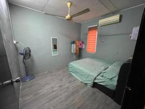 Habitación pequeña con cama y ventilador. en MP Homestay Lost world of tambun en Kampong Batu Lapan
