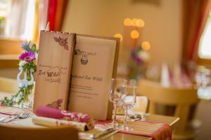 een boek bovenop een tafel met wijnglazen bij Alpenhotel zur Wildi in Wiler