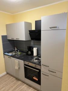 a kitchen with a stove and a white refrigerator at Pension Auszeit Ferienwohnung in Bad Neuenahr-Ahrweiler +13 photos