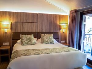 a bedroom with a large white bed with wooden walls at Hotel Princesa Parc in Arinsal