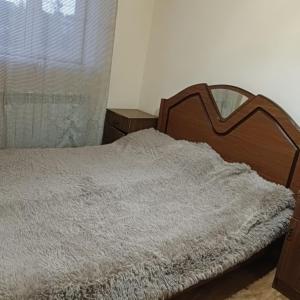 um quarto com uma cama com uma cabeceira em madeira e uma janela em Дом для гостей em Guiumri