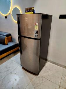 a metallic refrigerator in a room with a couch at Twilight Villa ll Swimming Pool ll AC ll BBQ ll 2BHK in Lonavala
