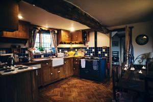 een keuken met houten kasten en een zwarte koelkast bij Long Cover Cottage in Tenbury