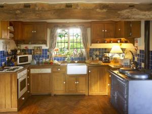 een keuken met houten kasten en een raam bij Long Cover Cottage in Tenbury