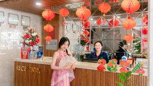 dos mujeres frente a un mostrador con faroles de papel en Gold Hotel Da Nang by Haviland, en Da Nang