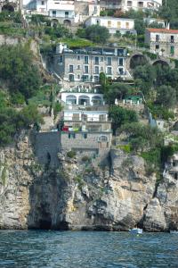 a building on the side of a cliff next to the water at Hotel Villa Maria Pia in Praiano