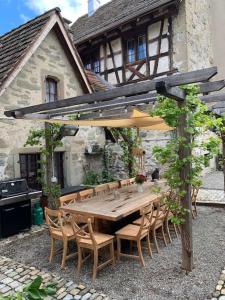 a wooden table with chairs and an umbrella in front of a house at Luxury 250 yr old Swiss farm with wine cellar in Rüschlikon