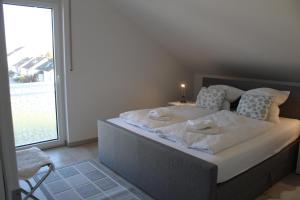um quarto com uma cama com lençóis brancos e uma janela em Ferienwohnung Seelicht em Uhldingen-Mühlhofen
