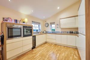 a kitchen with white cabinets and a clock on the wall at Host & Stay - The Willows in Teversal