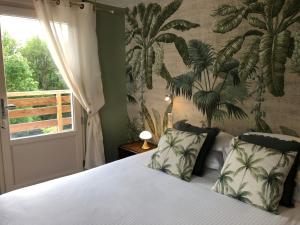 a bedroom with a bed with a tropical wallpaper at Logis Hôtels Troglododo in Azay-le-Rideau